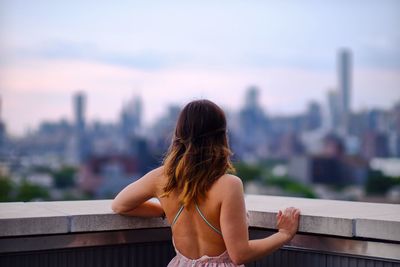 Rear view of young woman looking at cityscape from balcony