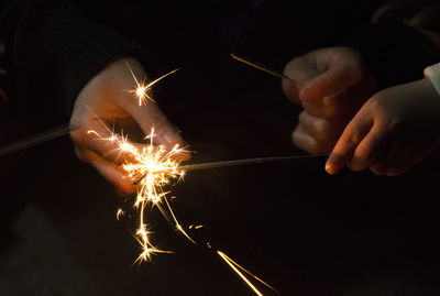 Close-up of hands holding sparklers at night