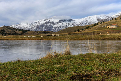 Scenic view of lake by snowcapped mountains against sky