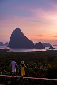 Rear view of women on mountain against sky during sunset