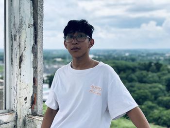 Portrait of young man standing against sky