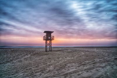 Lifeguard hut on beach against sky during sunset