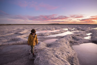 One kid walks across saltworks pools at sunset in guerrero negro