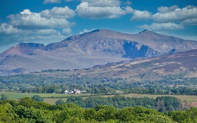 Scenic view of landscape and yr wyddfa/ snowdon against summer  sky