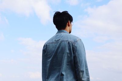 Rear view of man standing against cloudy sky