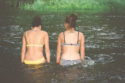 Rear view of young woman standing in river