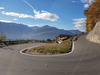 Road by mountains against sky