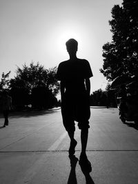 Rear view of silhouette man standing on footpath against sky