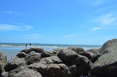 Rocks on beach against blue sky