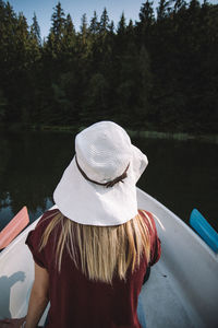 Rear view of woman standing by boat on lake