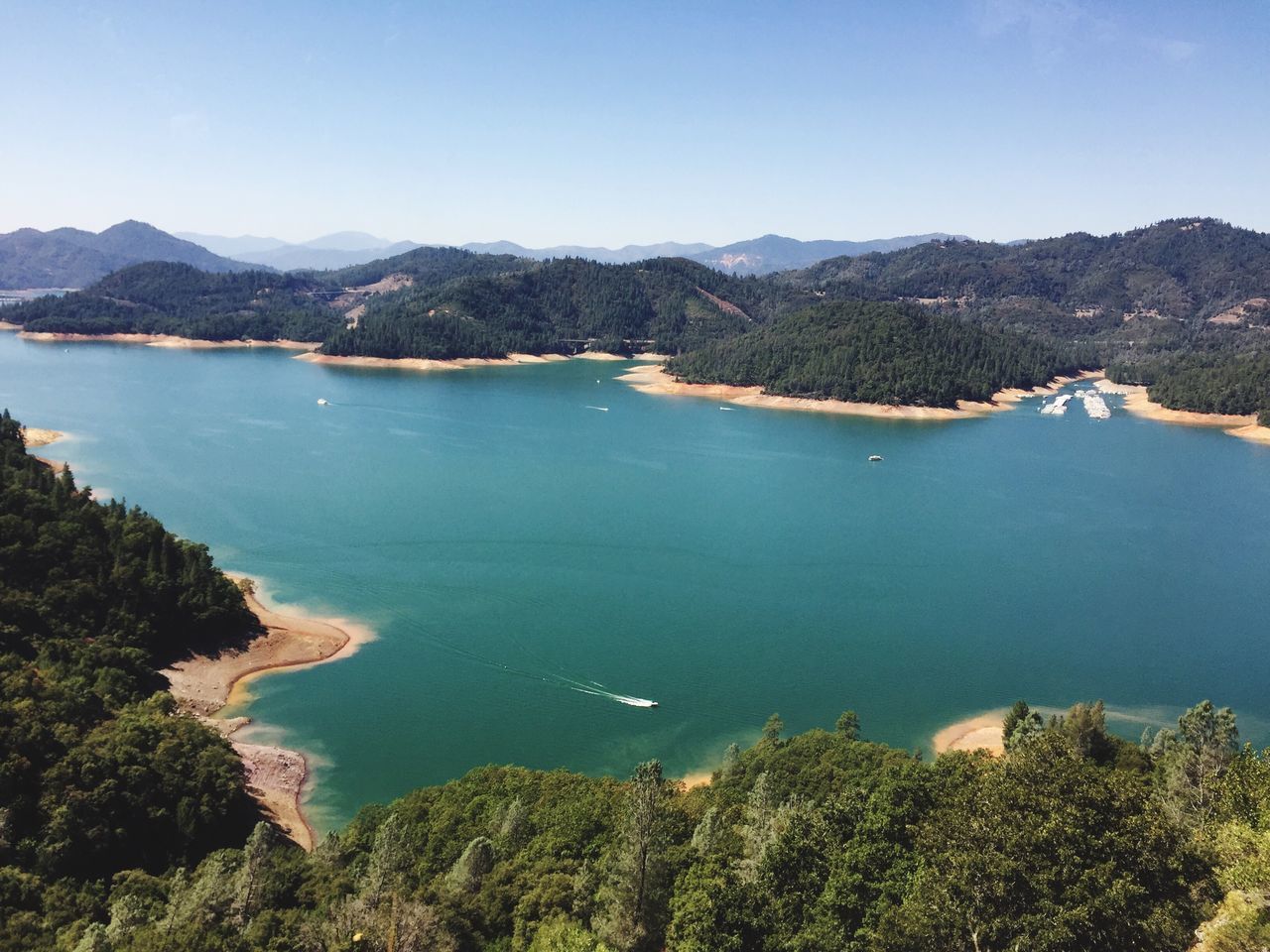 blue, water, tranquil scene, scenics, mountain, high angle view, tranquility, nautical vessel, clear sky, tree, beauty in nature, sea, calm, mountain range, nature, coastline, day, outdoors, solitude, non-urban scene, no people, green, seascape, remote, non urban scene, shore, ocean