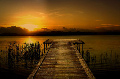 Wooden pier over lake against sky during sunset