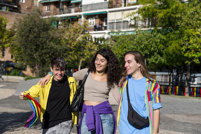 Young diverse friends walking on the street with the lgbt rainbow flag.