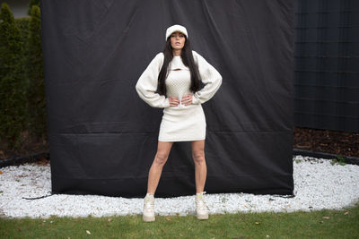 Portrait of young woman standing against wall