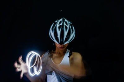 Man making light painting while standing against black background