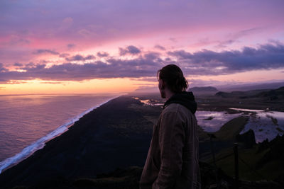 Woman looking at sea against sky during sunset