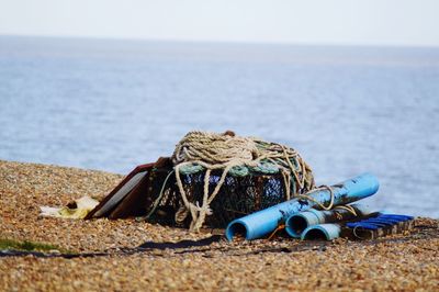 Fishing net with rope and pipes at beach against sky