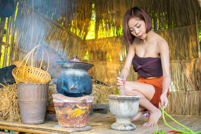 Full length of woman preparing food in hut