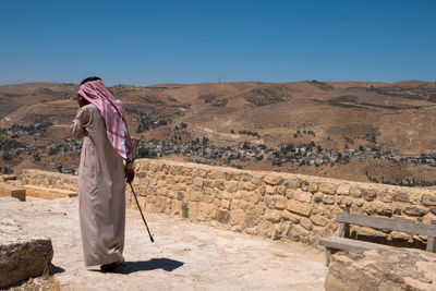 Rear view of man standing on landscape against clear sky