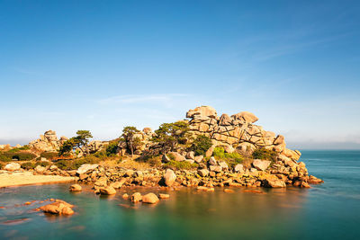 Rock formations by sea against blue sky