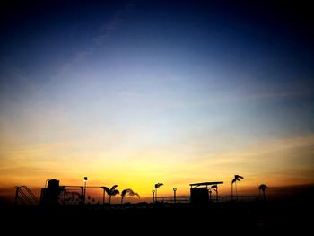 Silhouette street against orange sky