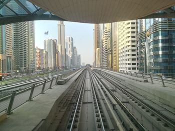 Railroad tracks amidst buildings in city against sky