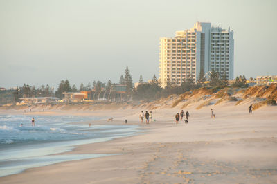 People on beach in city against sky