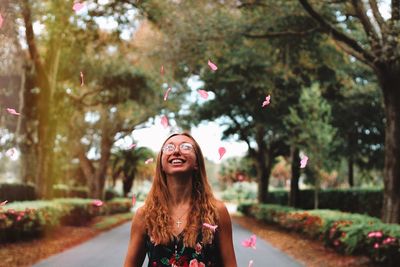 Portrait of smiling young woman standing against trees