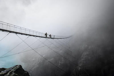 Low angle view of footbridge during foggy weather against sky