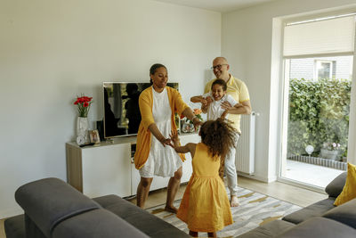 Happy children with parents dancing in living room at home