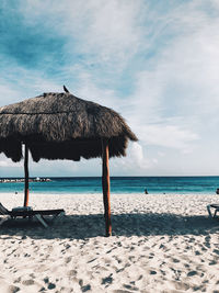 Thatched roof on beach against sky