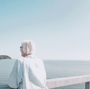 Rear view of woman on beach against clear sky