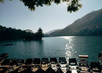 Boats moored by lake against clear sky