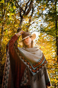 Portrait of a young woman in autumn park, dressed poncho, with hat