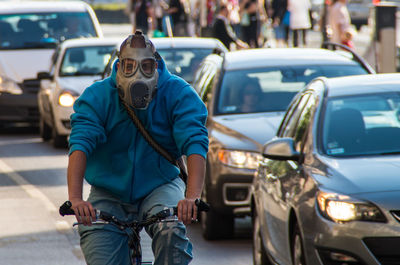 Man wearing gas mask while riding bicycle on road
