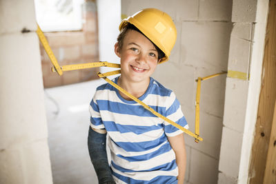 Portrait of smiling young man standing against wall