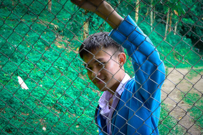 Portrait of boy by chainlink fence