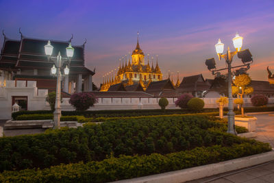 Illuminated building against sky during sunset