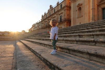 Full length of girl standing on steps in city