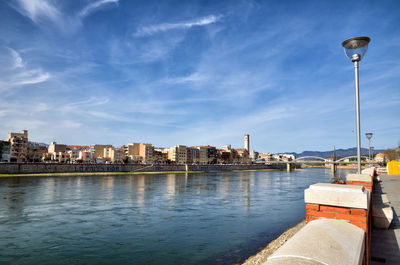 River by buildings in city against sky