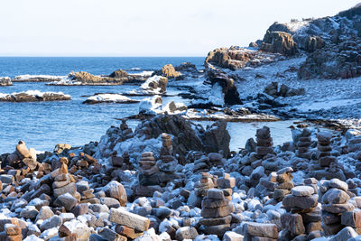 Rocks on beach by sea against sky