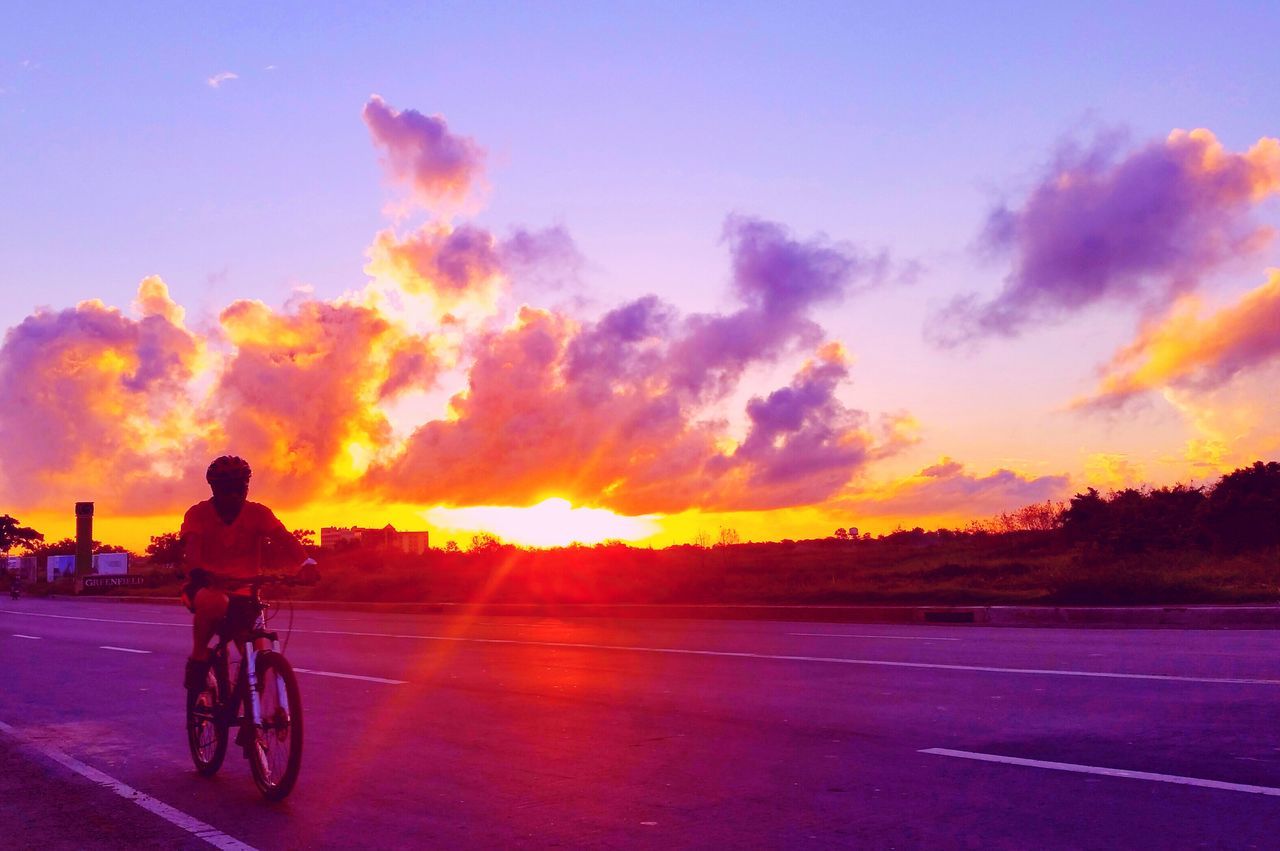 sunset, transportation, land vehicle, sky, road, mode of transport, cloud - sky, orange color, sun, bicycle, lifestyles, street, car, on the move, full length, riding, silhouette, men