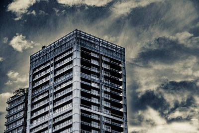 Low angle view of apartment building against cloudy sky