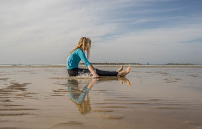 Full length side view of girl sitting on shore at beach