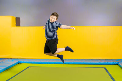 Rear view of boy jumping against yellow wall