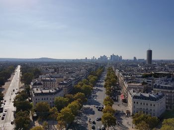 Aerial view of street and buildings in city against blue sky