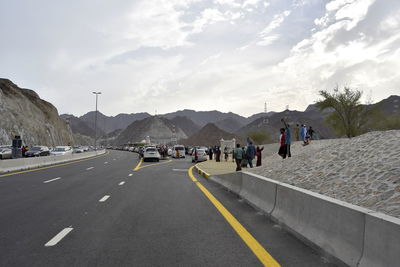 Group of people on road against sky