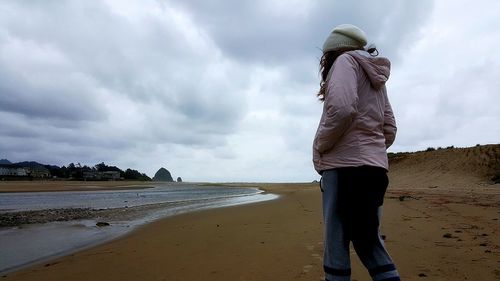 Rear view of woman standing on beach against sky