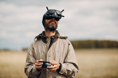 Portrait of man holding camera while standing outdoors