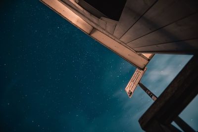 Low angle view of telephone pole against sky at night